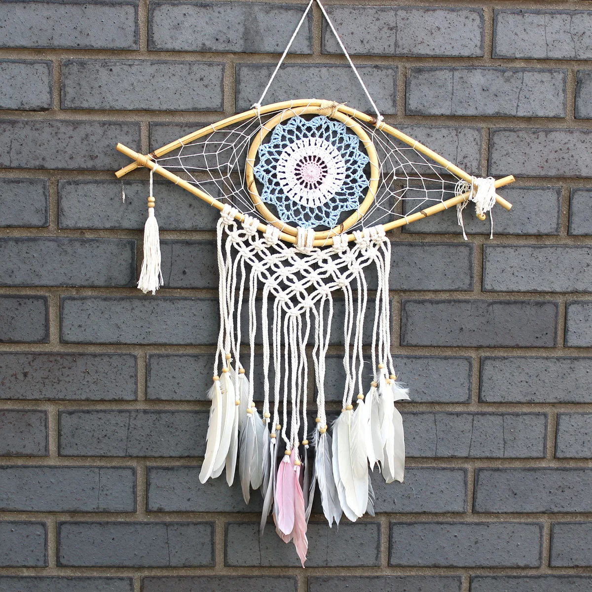 Medium macrame dream catcher featuring a blue and pink evil eye, white accents – a striking evil eye wall art piece.