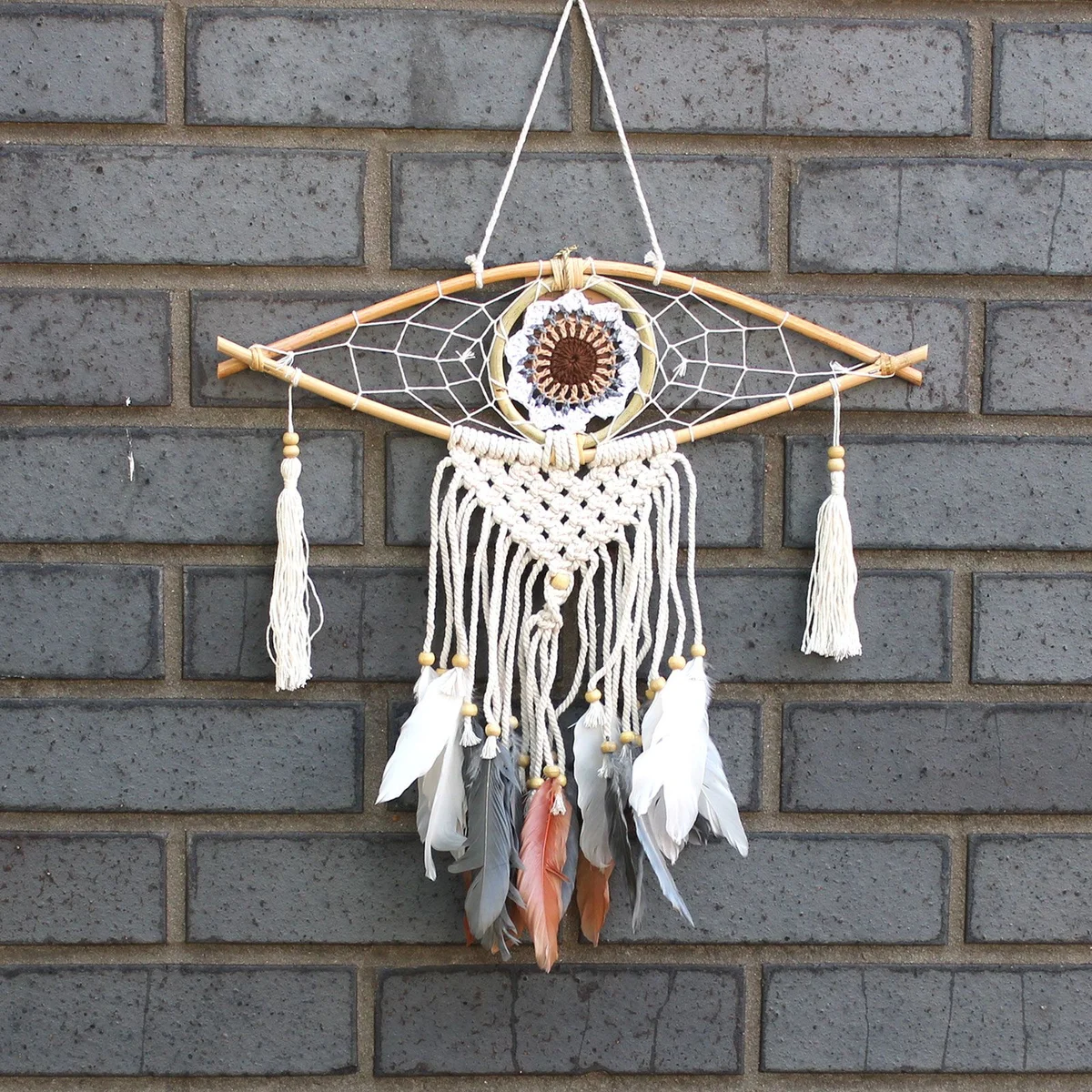 Small macrame dream catcher with evil eye motif, woven structure and natural thread.