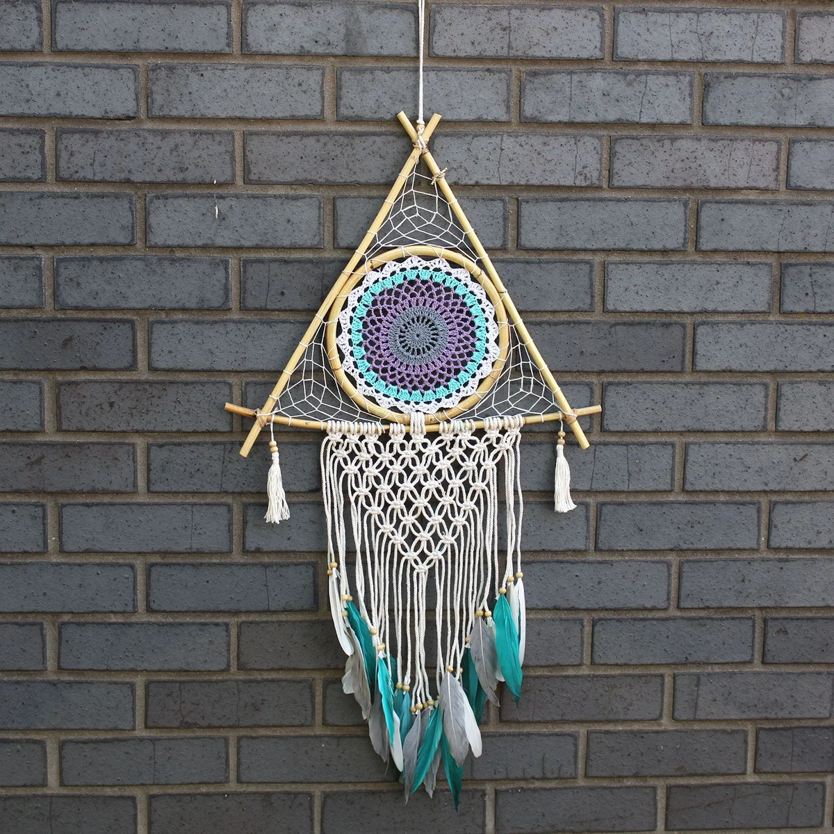 Large macrame dream catcher pyramid in white and turquoise threads, woven with intricate knotting.