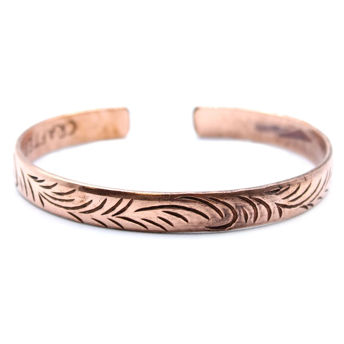 Slim copper Tibetan bracelet with intricate tribal swirl designs on a white background