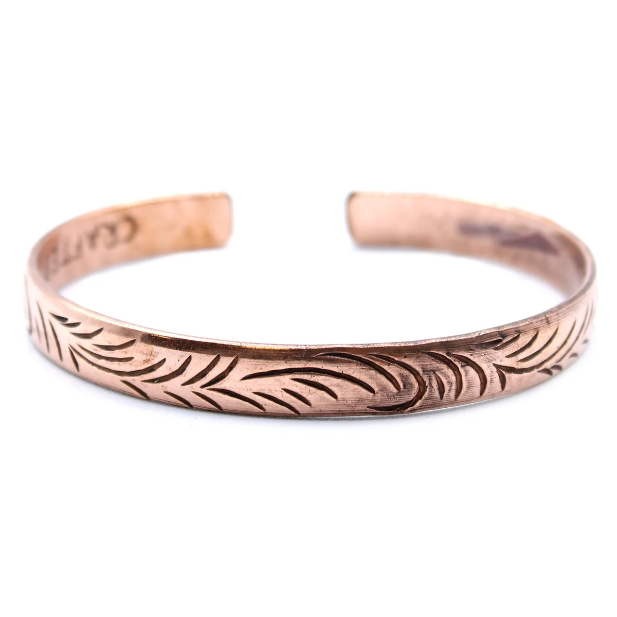 Slim Tibetan copper bracelet featuring intricate tribal swirl designs on a copper band, shown on a white background
