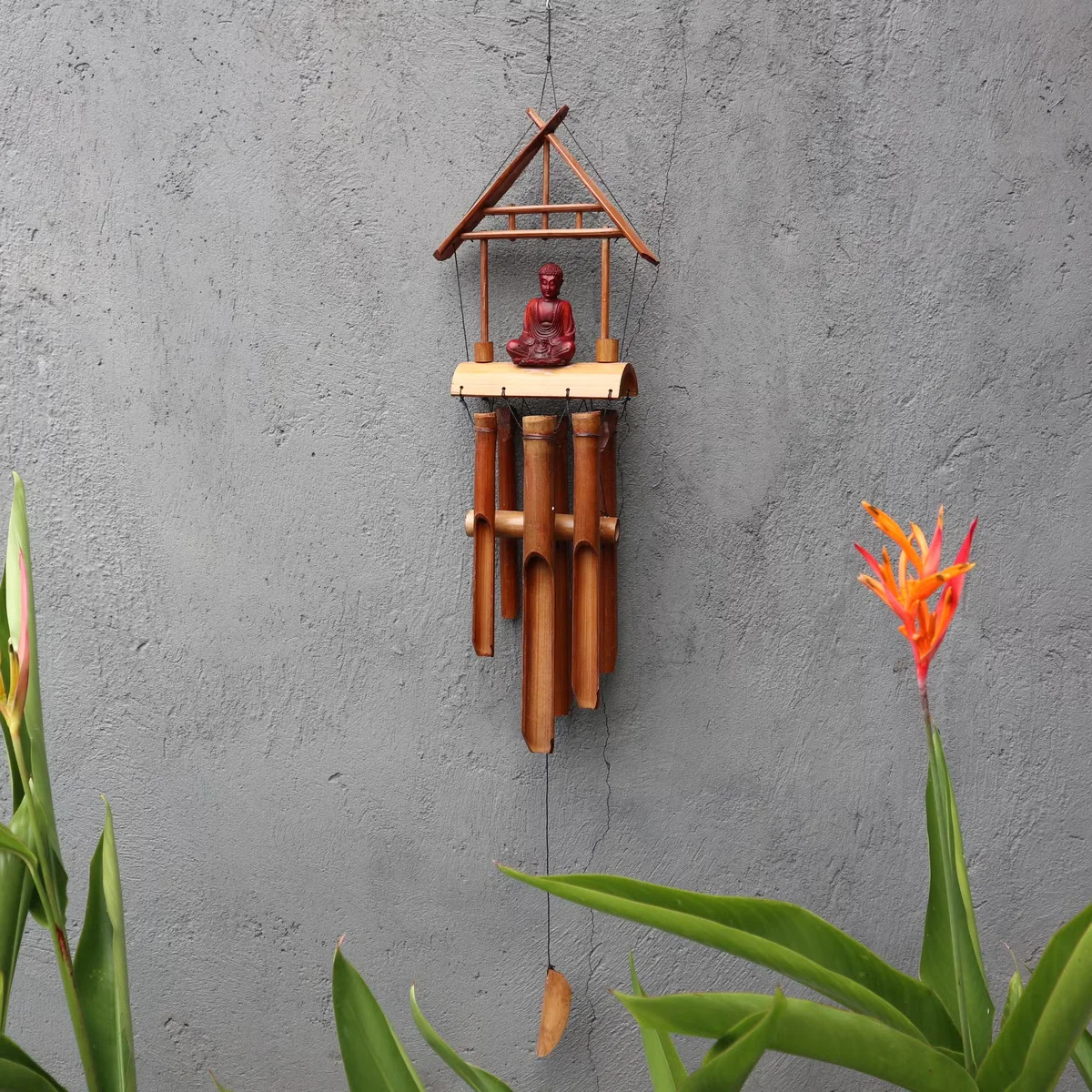 Brown Buddha 6 tube bamboo chime with natural finish hanging outdoors against a blurred background