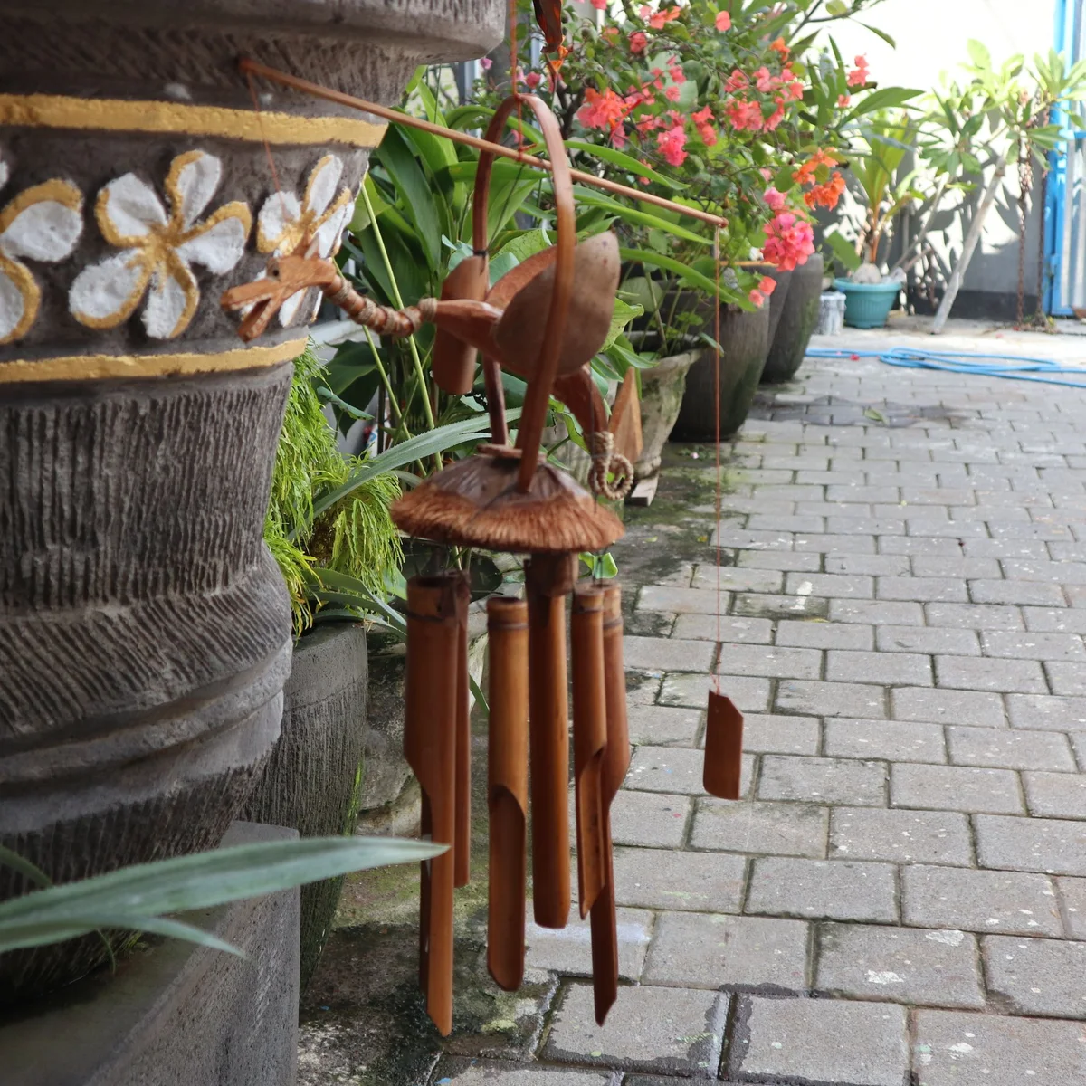 Natural finish bamboo windchime featuring a carved coconut dragon design hanging outdoors