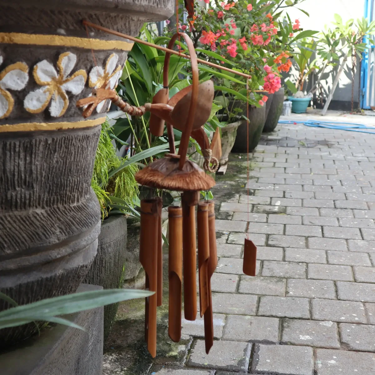 Natural finish windchime made of bamboo with a coconut dragon design hanging outdoors