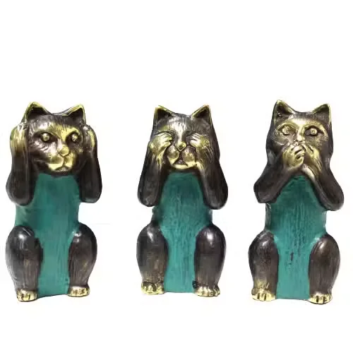 Set of three cat statues in brass showing see no evil, hear no evil, speak no evil poses on a white background