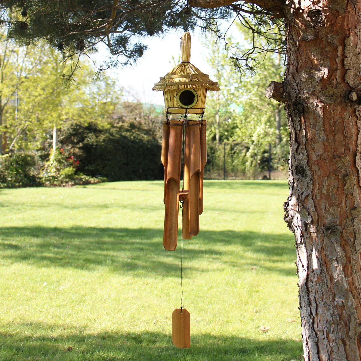 Round seagrass bird house with circular shape and hanging chimes, measuring 45x17cm against white background