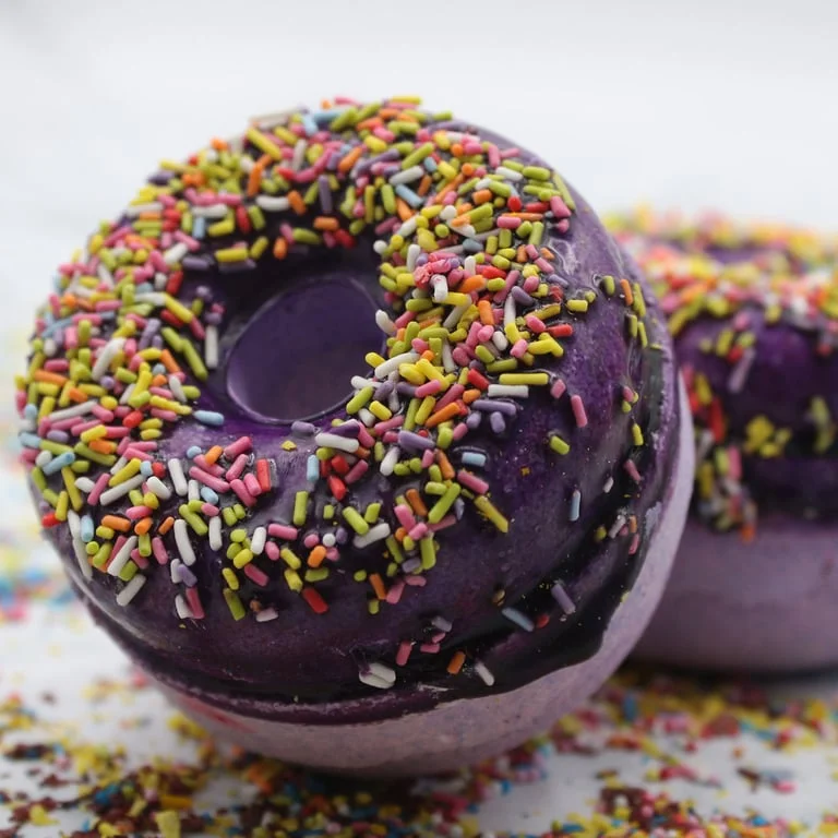 Blackberry and almond bath donuts arranged on a neutral background, a fruity bath bomb set.