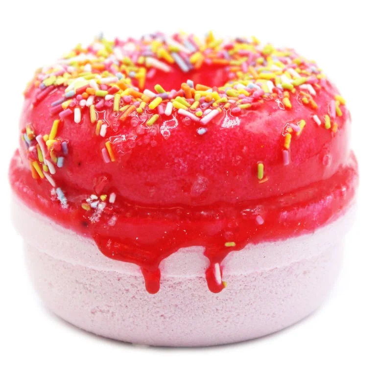 Strawberry banana bath bombs with pink and yellow donuts floating in a clear bathtub.