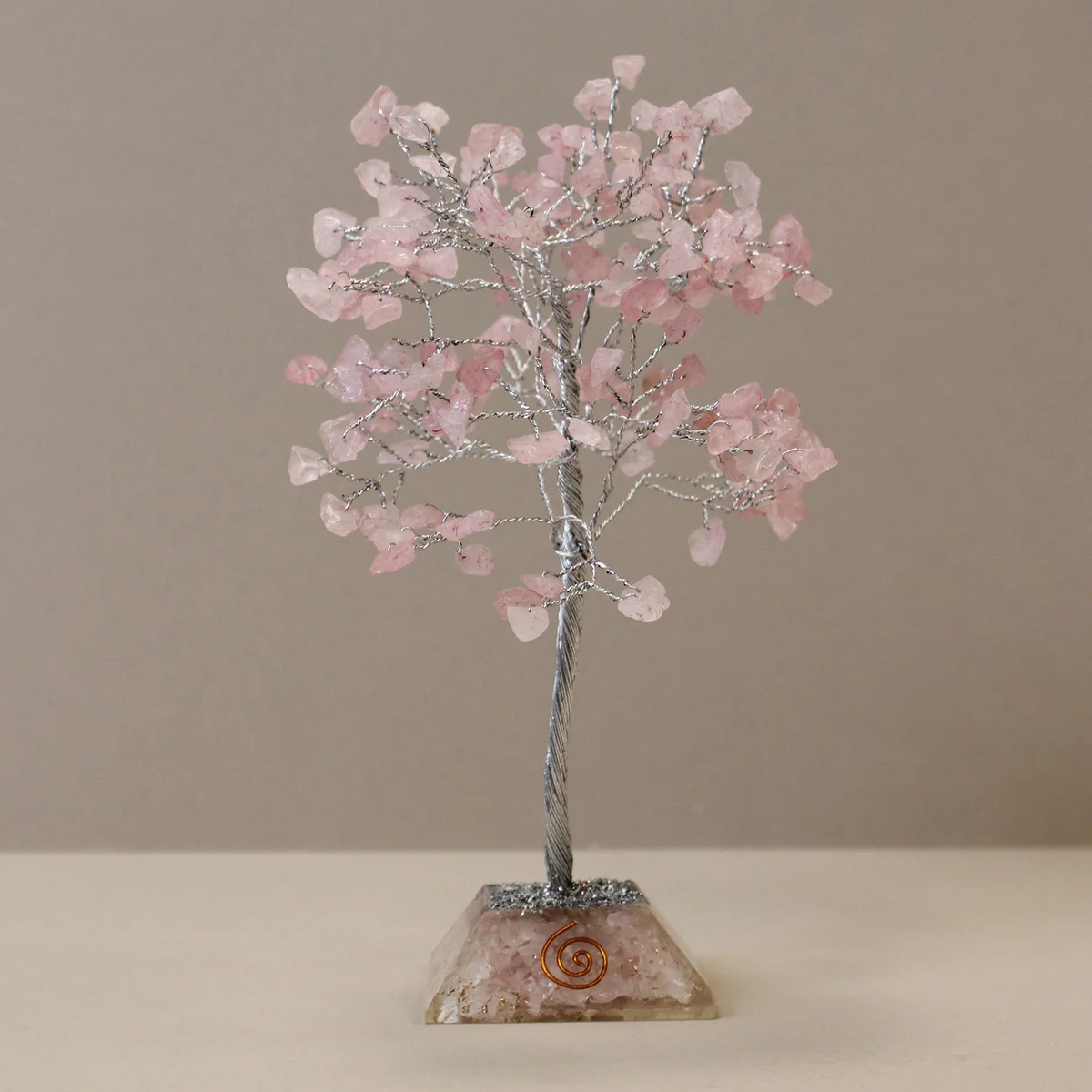 Gemstone tree with 160 rose quartz stones on a decorative organite base decoration against white background