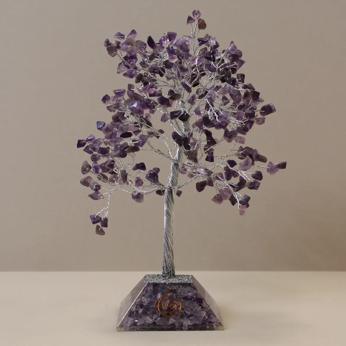 Gemstone tree ornament with purple amethyst stones and organite base on white background
