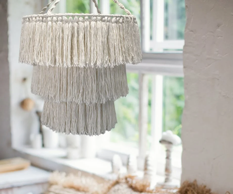 Macrame soft chandelier hanging from ceiling, natural materials, emitting soft chandelier light.