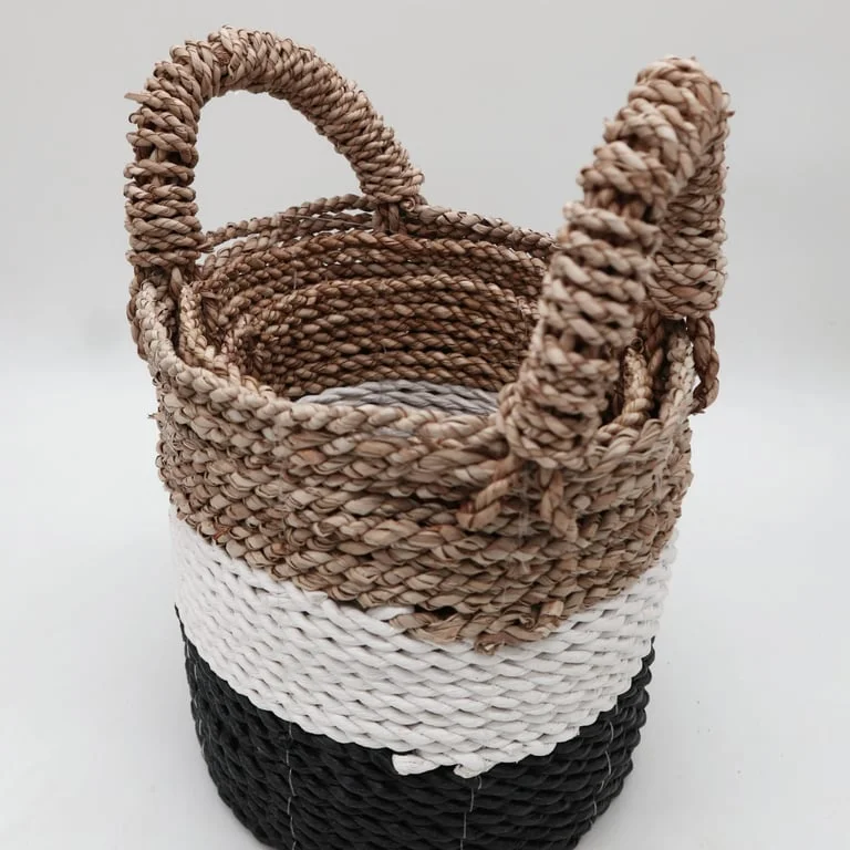 Set of natural seagrass baskets in dark grey, white and natural tones, arranged together on a clean surface.