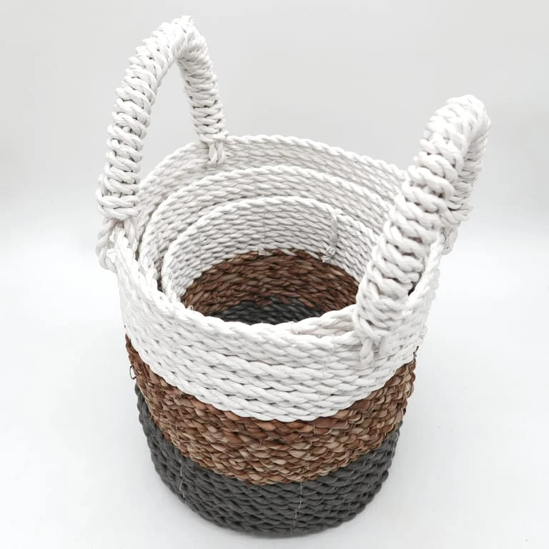 Three decorative seagrass baskets in grey, natural and white, displayed together in a set.