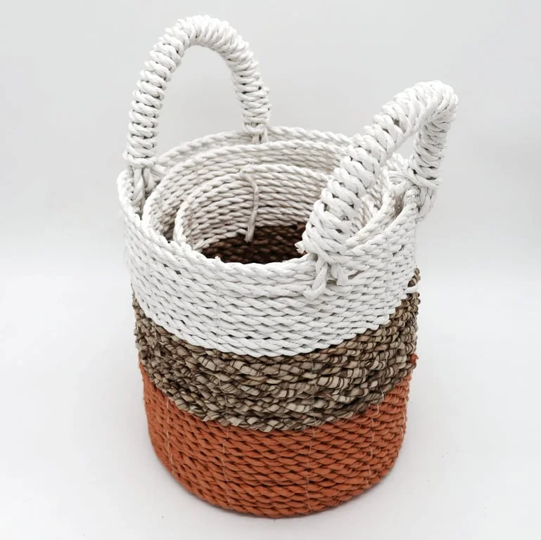 Set of three woven seagrass baskets in orange, natural, and white woven baskets.