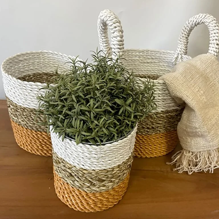 Three seagrass home storage baskets in orange, natural and white.