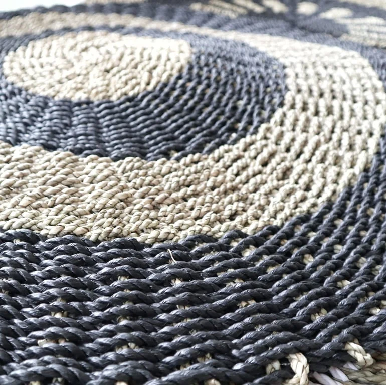 Round black and tan basket made of seagrass with circular pattern, 1 metre long