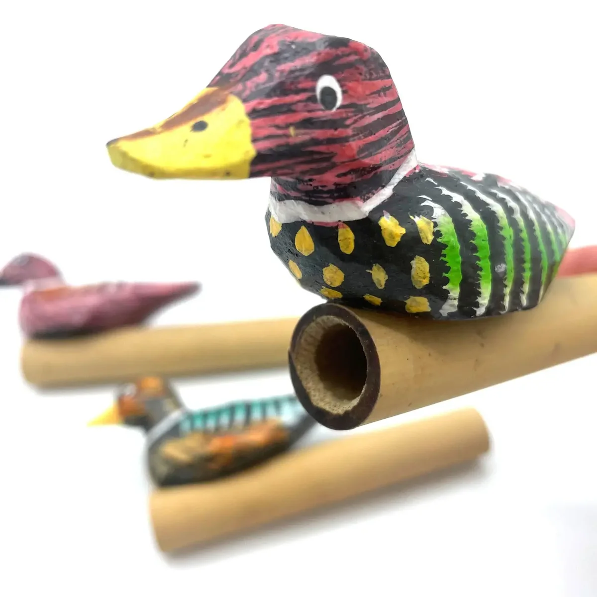 Small green duck-shaped animal sound whistle used for mimicking duck calls on a white background