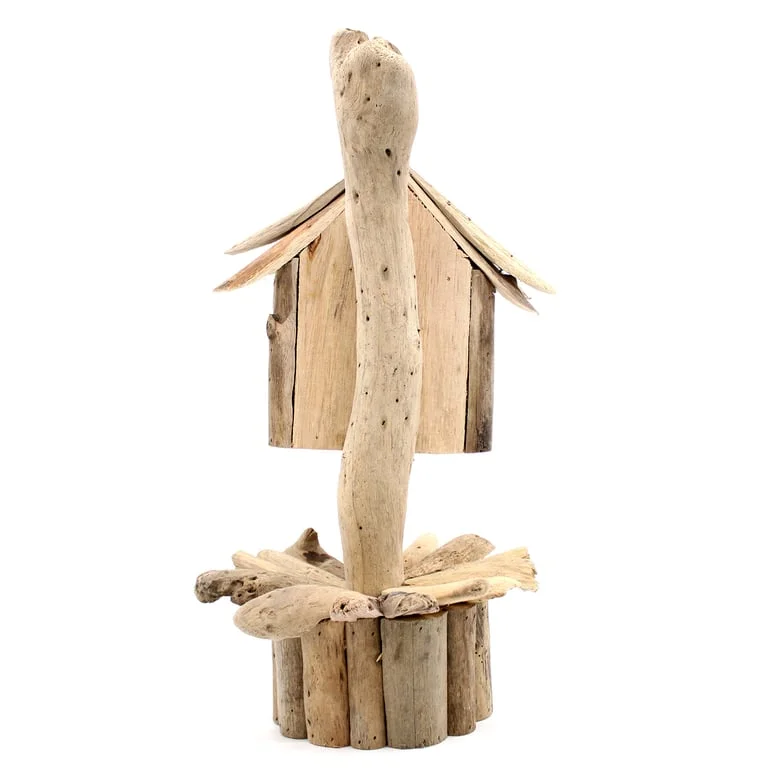 Wooden birdbox with stand placed on a wooden table surrounded by foliage