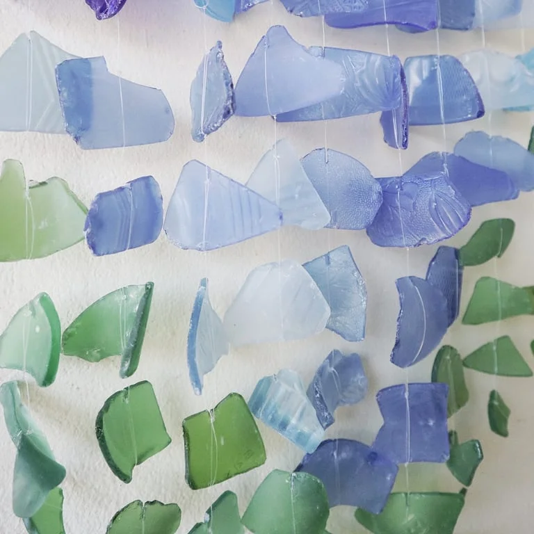 Abstract wall decor featuring three sticks in blue and green.