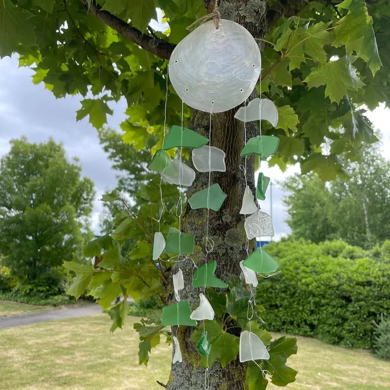 Green and white glass drop ornament from Copis & Glass, featured in a bright display.