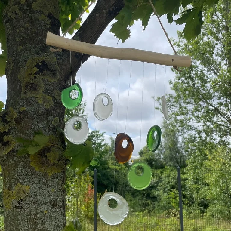 Assorted bottle bottom decorative wind chimes hanging on a string, creating a colorful arrangement.