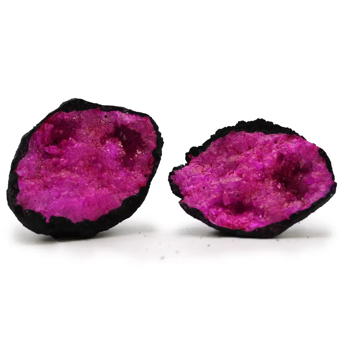 Dark red and pink coloured calsite black rock geode with crystalline interior on display against white background