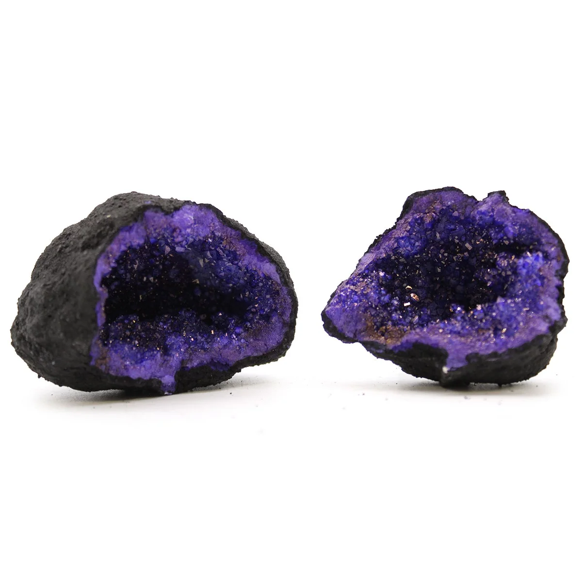 Coloured calsite geodes with black rock exterior and turquoise and purple crystal interiors on white background