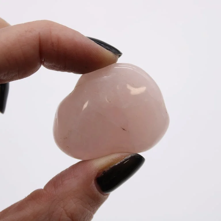 Medium-sized rose quartz African tumble stones, partially tumbling, gathered on a white background.