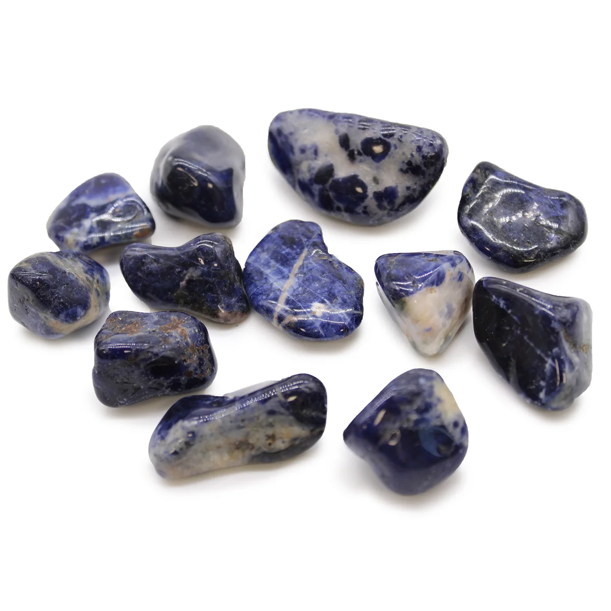 Medium tumble stones in pure blue sodalite, polished and smooth, arranged on a white background