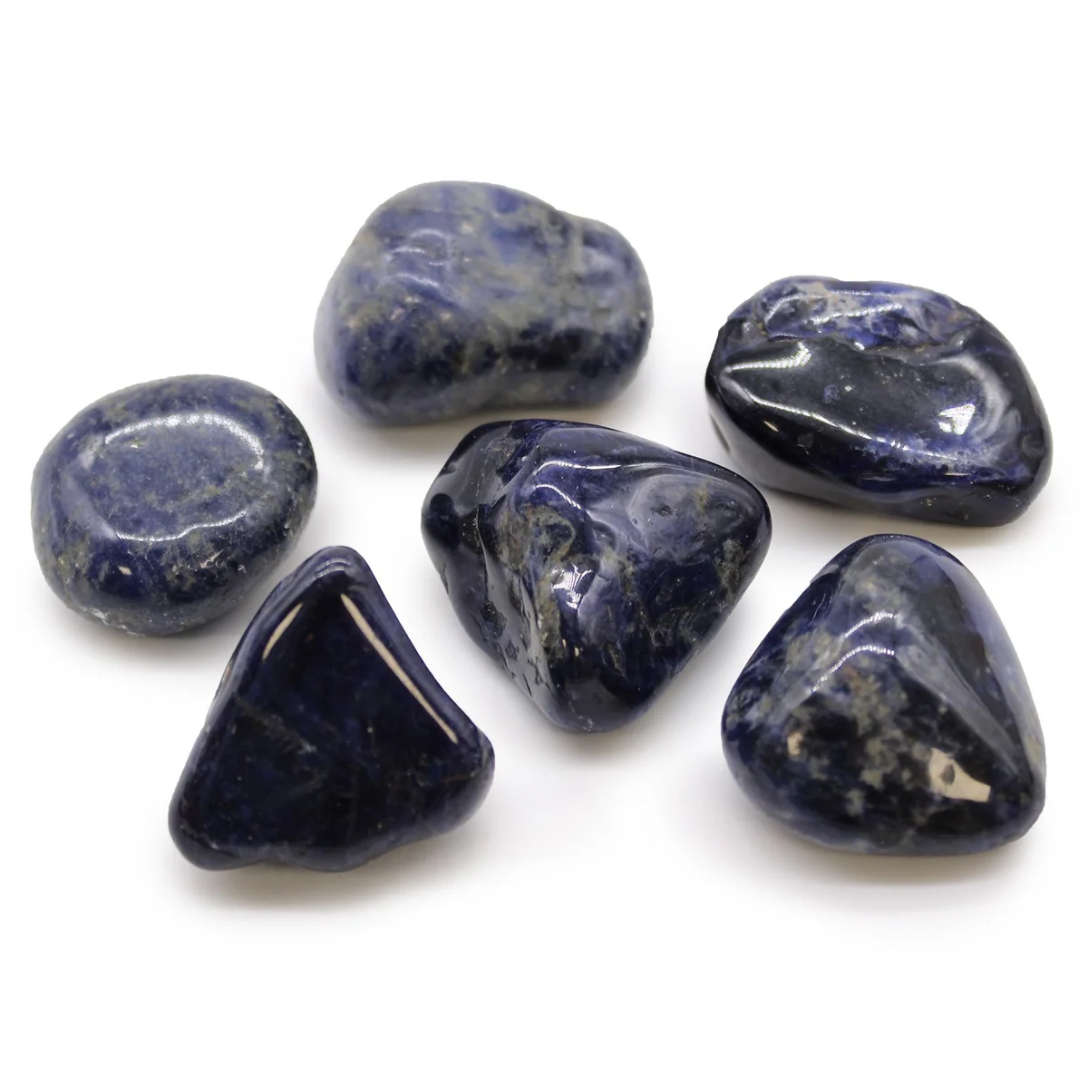 Large sodalite tumble stones in pure blue, polished and smooth, arranged on a white background
