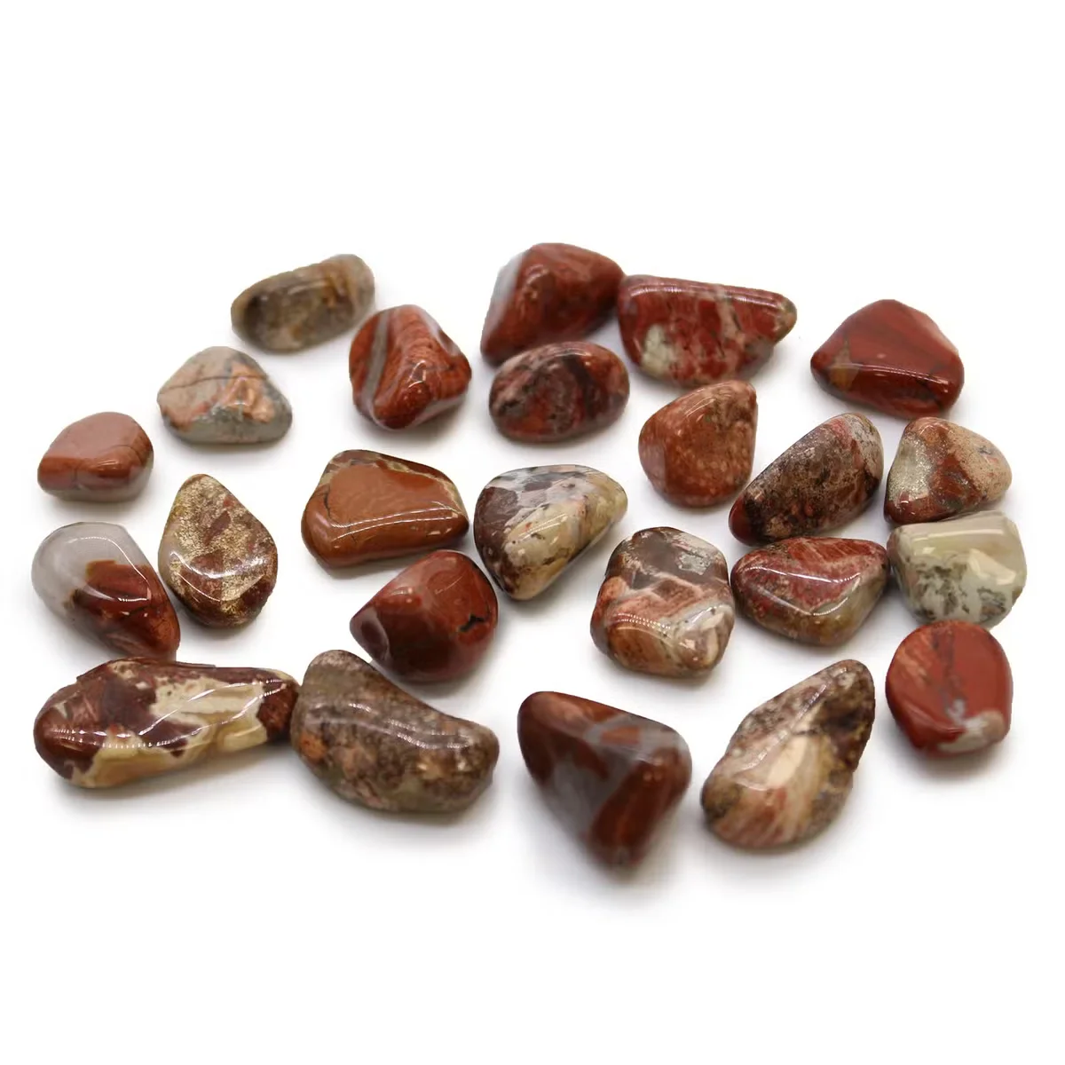 Small tumble stones made of light brecciated jasper, polished and irregularly shaped, shown on a white background