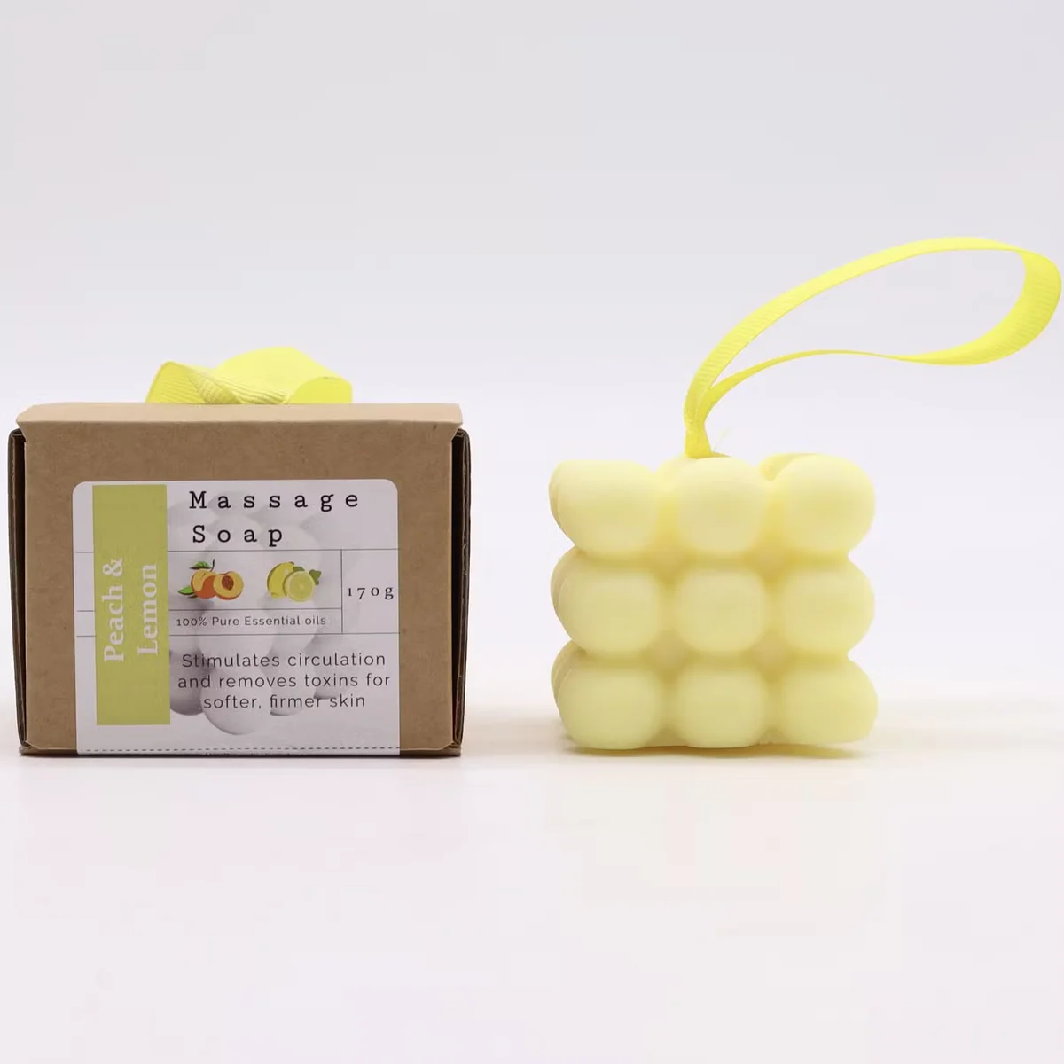 Box of single massage soap bars in peach and lemon, showing a lemon soap with a fresh citrus design.