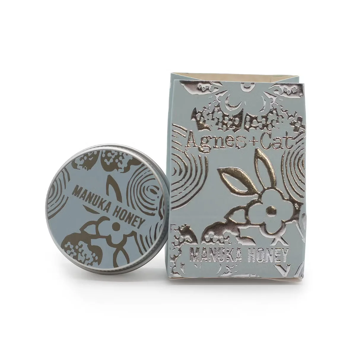Agnes + Cat lip balm tube with Manuka Honey label on a white background, showing product branding clearly
