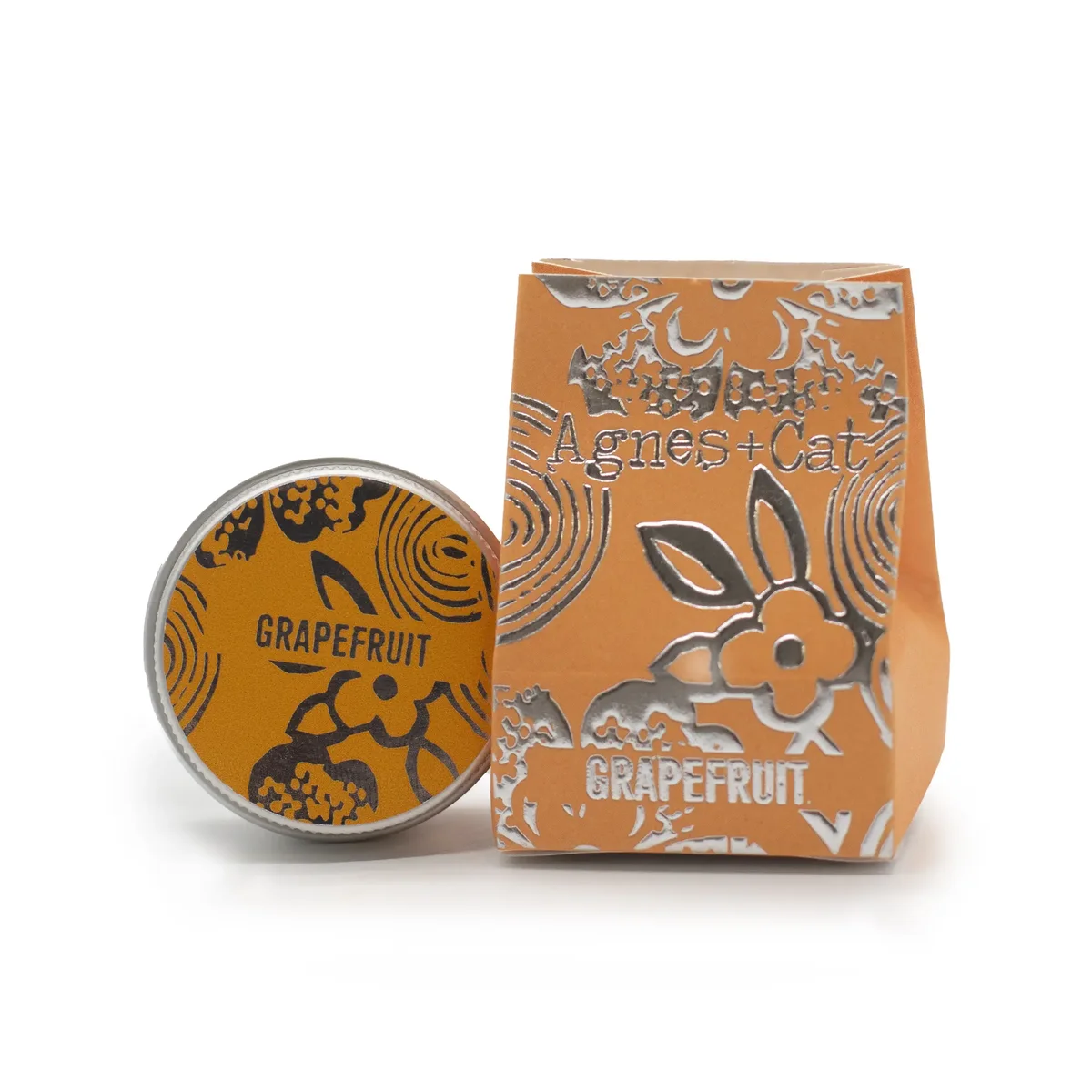 Agnes + Cat hydrating lip balm in grapefruit flavor with simple white and orange packaging on a white background