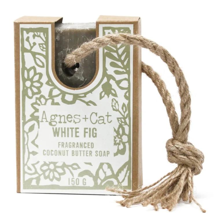 White fig soap hanging on a rope, displayed on a wooden background