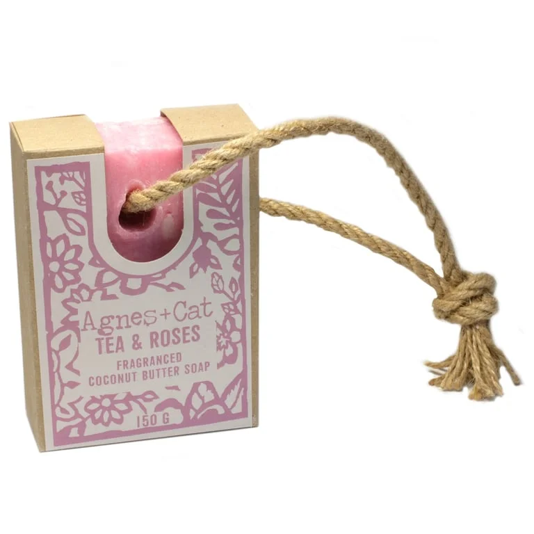 Tea and roses soap hanging on a rope, light pink soap with floral patterns wrapped in a ribbon.
