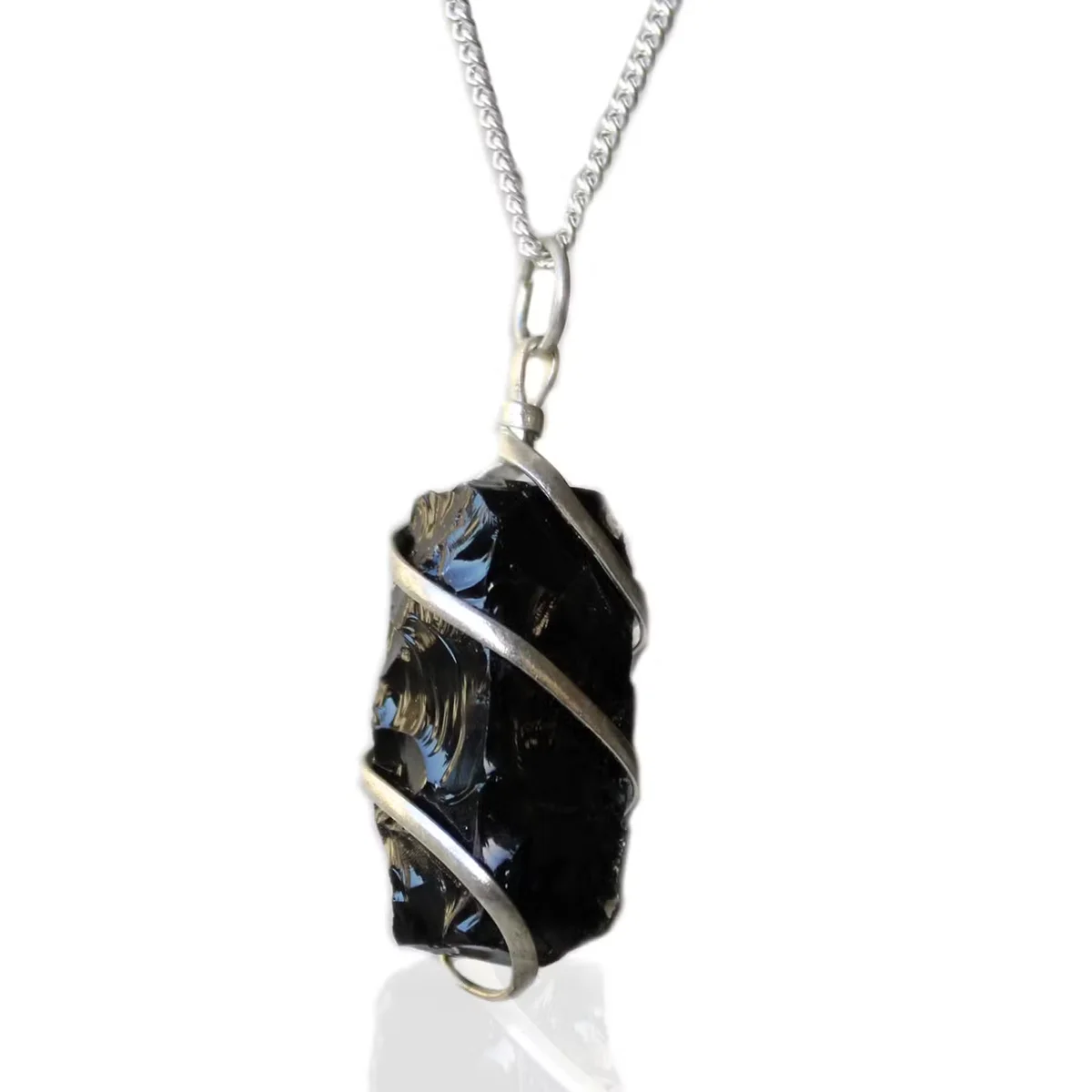 Close-up of cascade gemstone necklace featuring rough black onyx wrapped in silver wire on a white background
