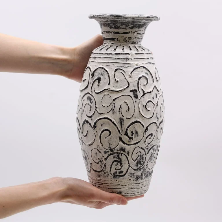 Cream coloured vase with swirls design, rounded shape.