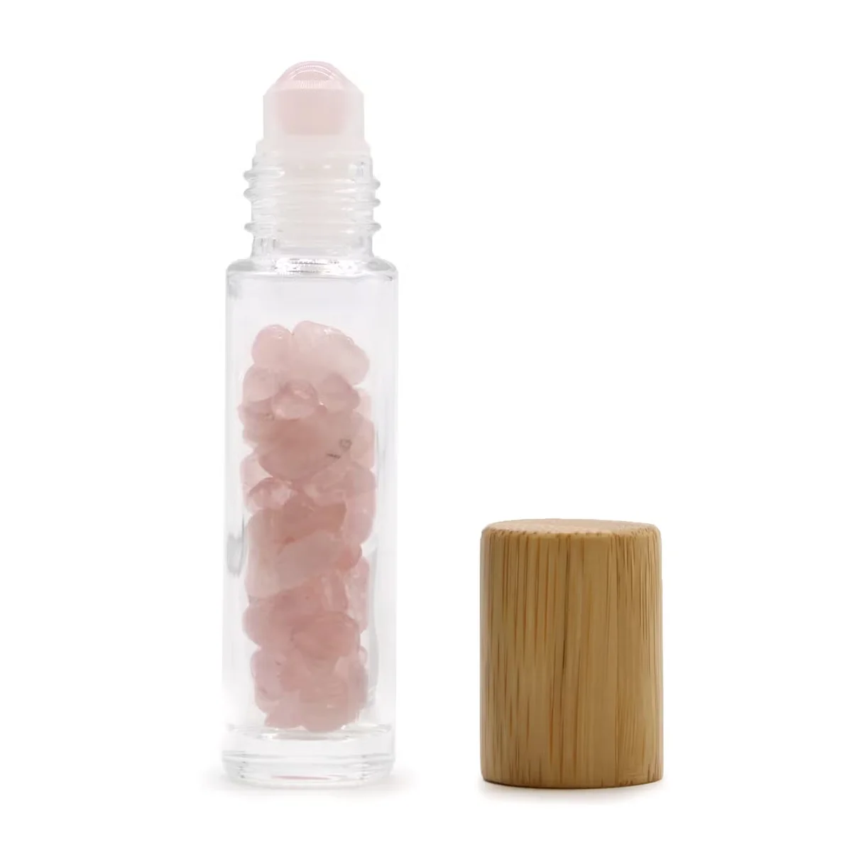 Essential oil roller bottle with a rose quartz body and wooden cap, held between fingers.
