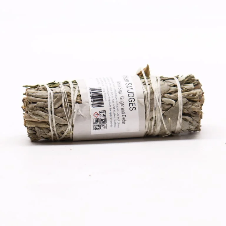 Sage smudge bundle of white sage, ginger and cedar sticks on a wooden tray