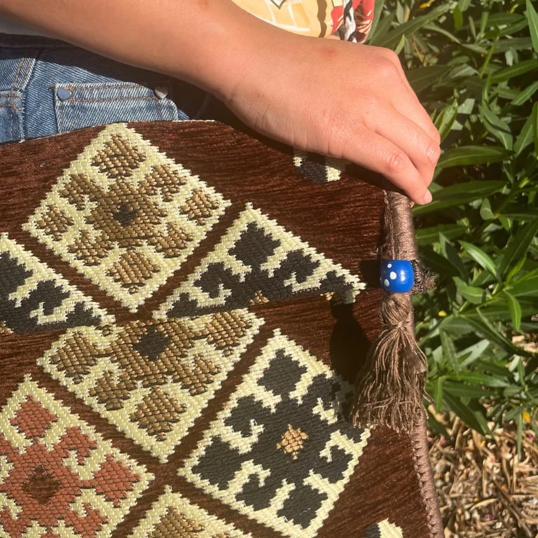 Chocolate kilim bag, messenger festival bag with woven design, displayed against plain backdrop.