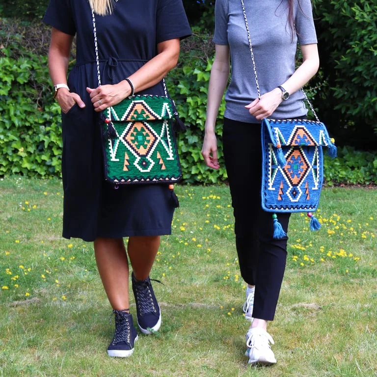 Emerald green kilim messenger bag, a festival shoulder bag featuring tribal patterns and a slanted shoulder strap.