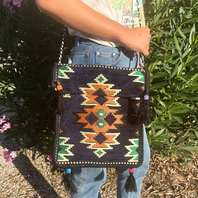 Front view of dark navy messenger bag featuring a kilim pattern, styled as a festival messenger bag