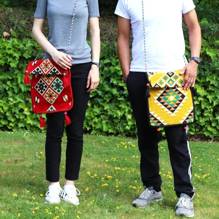 A red kilim messenger bag displayed on a neutral background, featuring a woven pattern and sturdy canvas material.