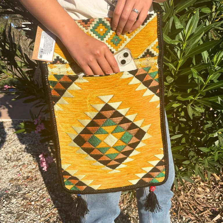 Yellow kilim bag, rectangular messenger style with folded flap and strap, displayed on black background.