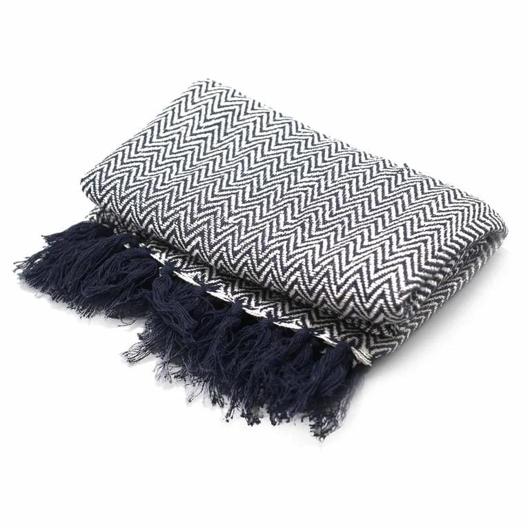 Navy blue zigzag patterned decorative throw, soft fabric folded on a minimalist white shelf—perfect for adding style with decorative throws UK.