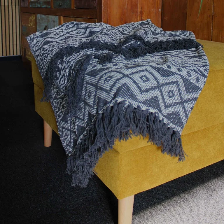 Grey geometric patterned soft decorative throw draped over a sofa, showcasing boho style design.