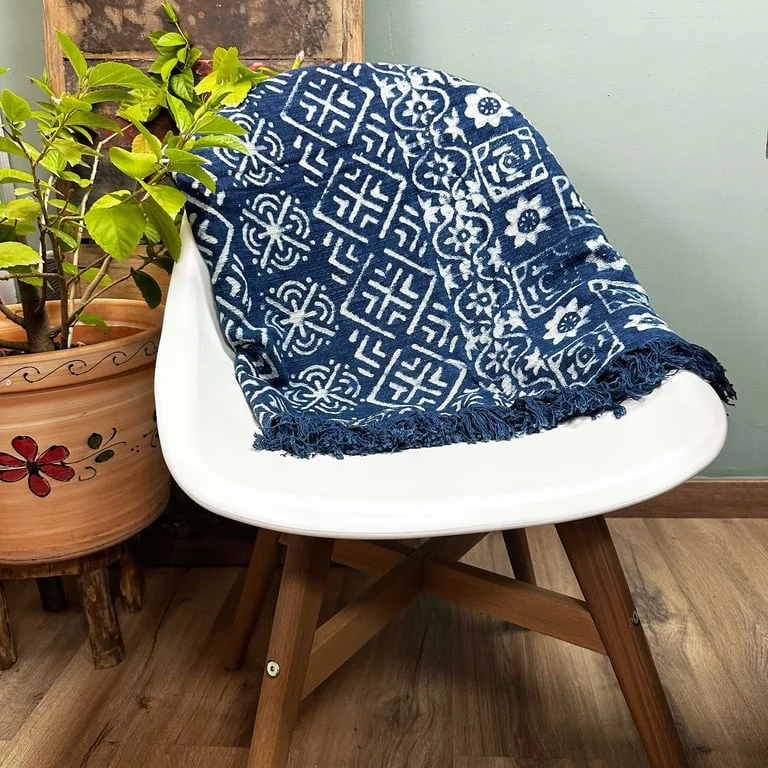 Handmade indigo throw with desi stripe pattern laid on a wooden floor, colour rich fabric visible in shot
