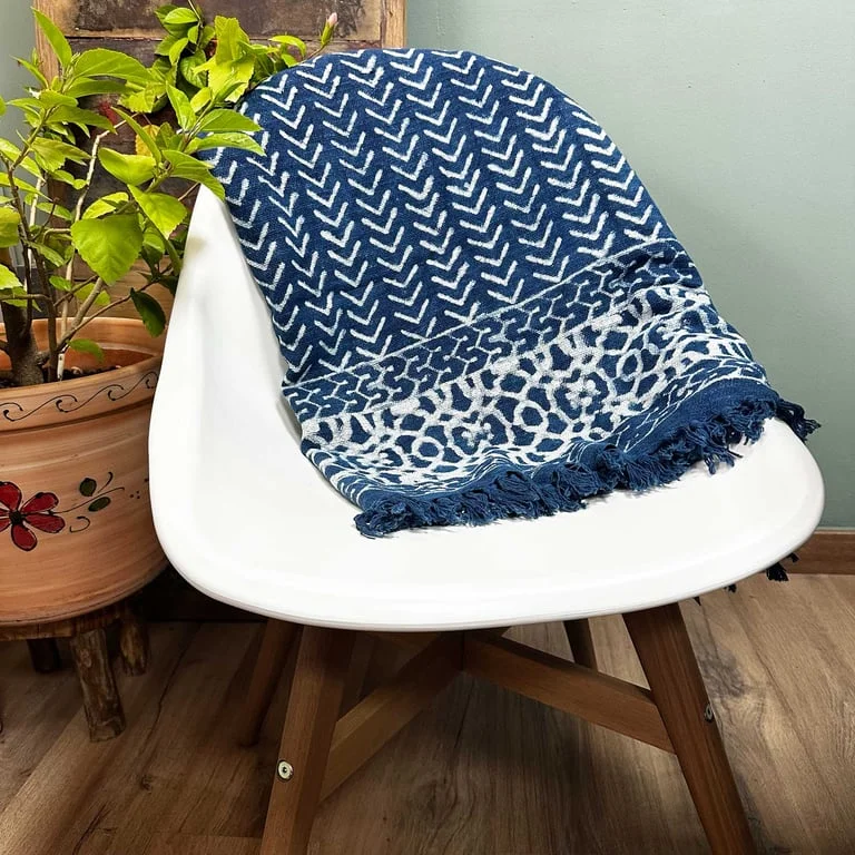 Handmade indigo throw blanket draped over a sofa, showcasing its deep hue and soft texture