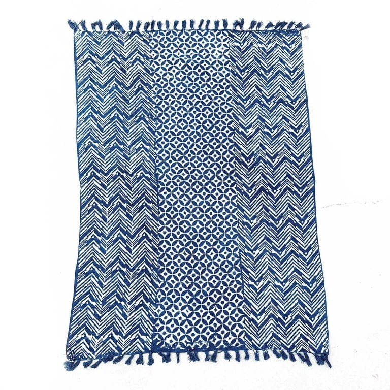 Handmade indigo throw blanket showing a wave pattern laid on a neutral surface.